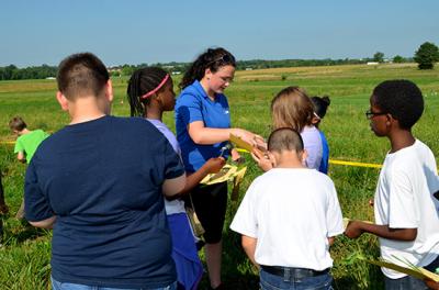 Sydney Beidleman, center, UK forage intern, helps Millcreek Elementary students identify weeds. Sydney Beidleman, center, UK forage intern, helps Millcreek Elementary students identify weeds.