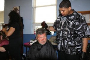 Brandon Merriweather cuts the hair of one of the men who came to the event at the New Life Day Center. PHOTO: Avis Sampson, UK senior